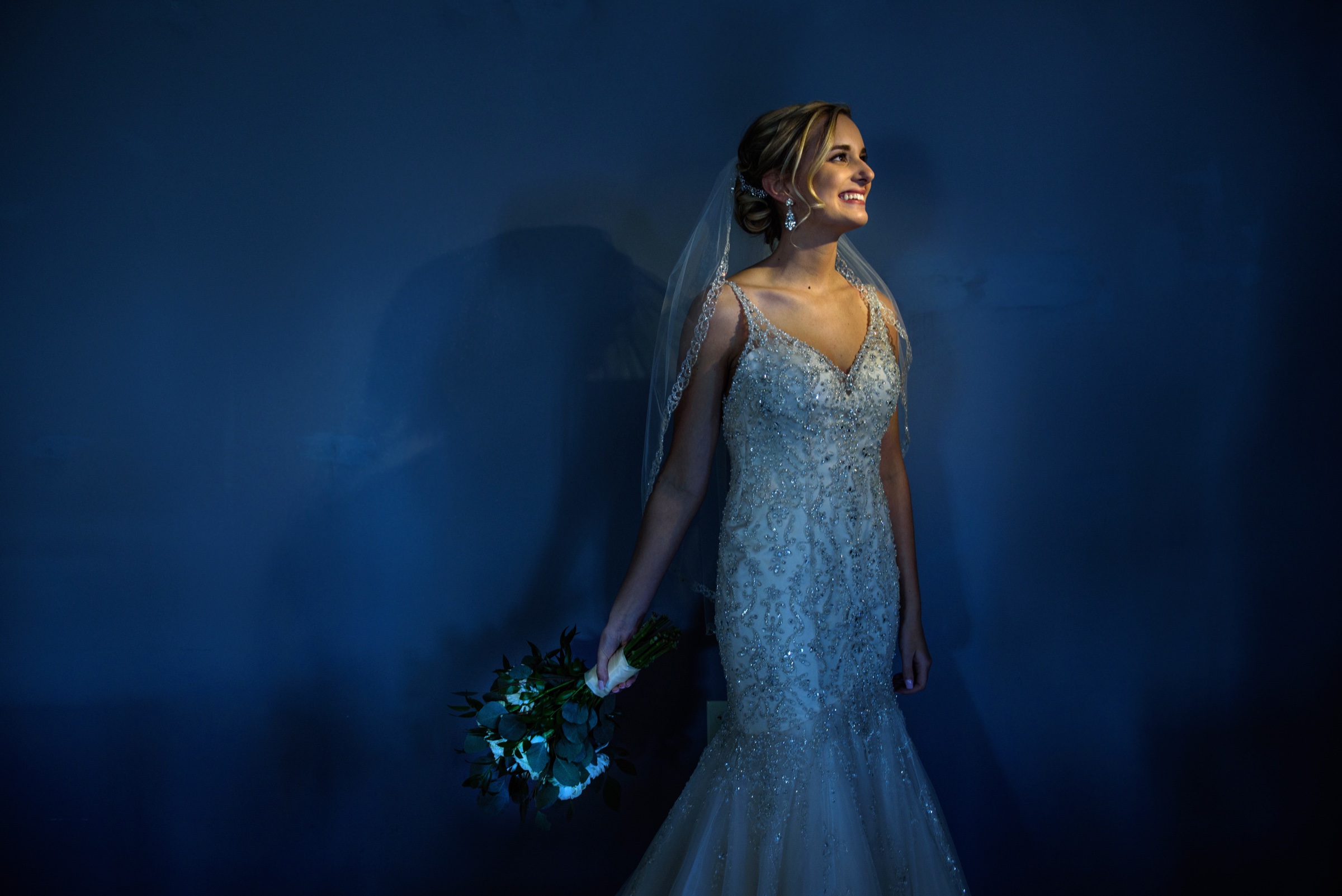 Bride in a blue gown against a dark wall