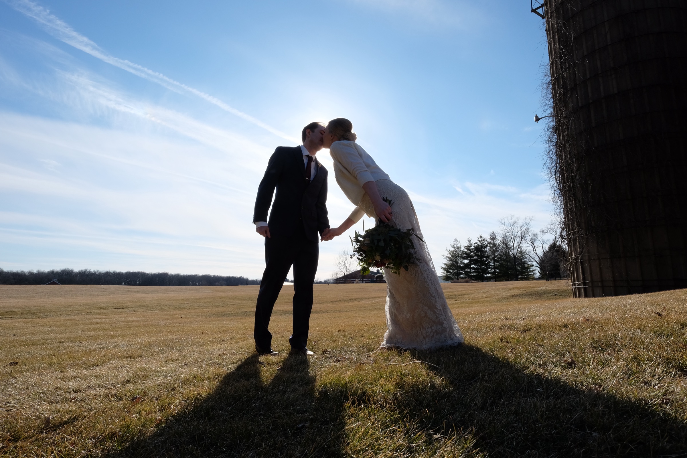 Couple kissing in a field at sunset