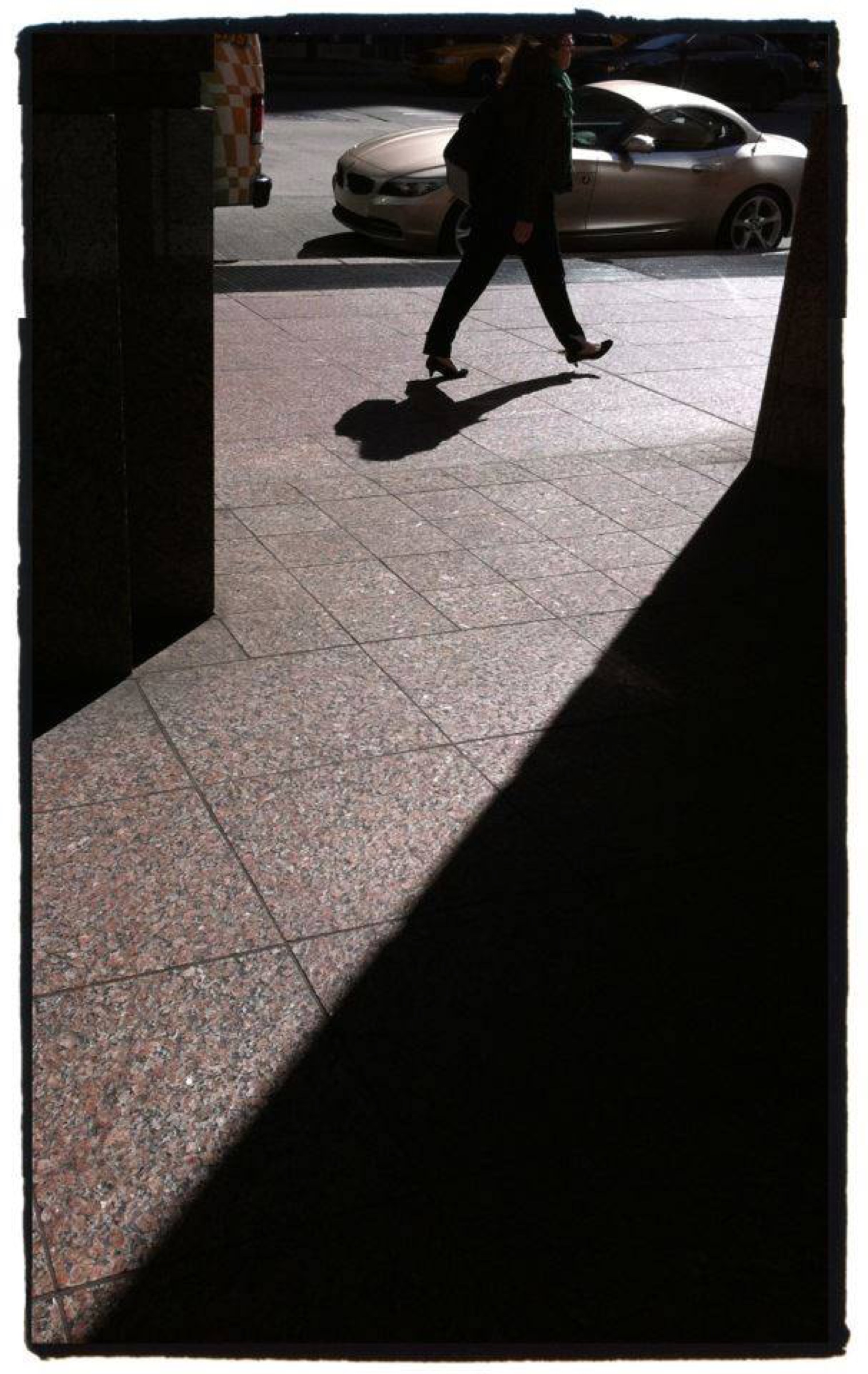 Lone walker crossing a shadowed plaza