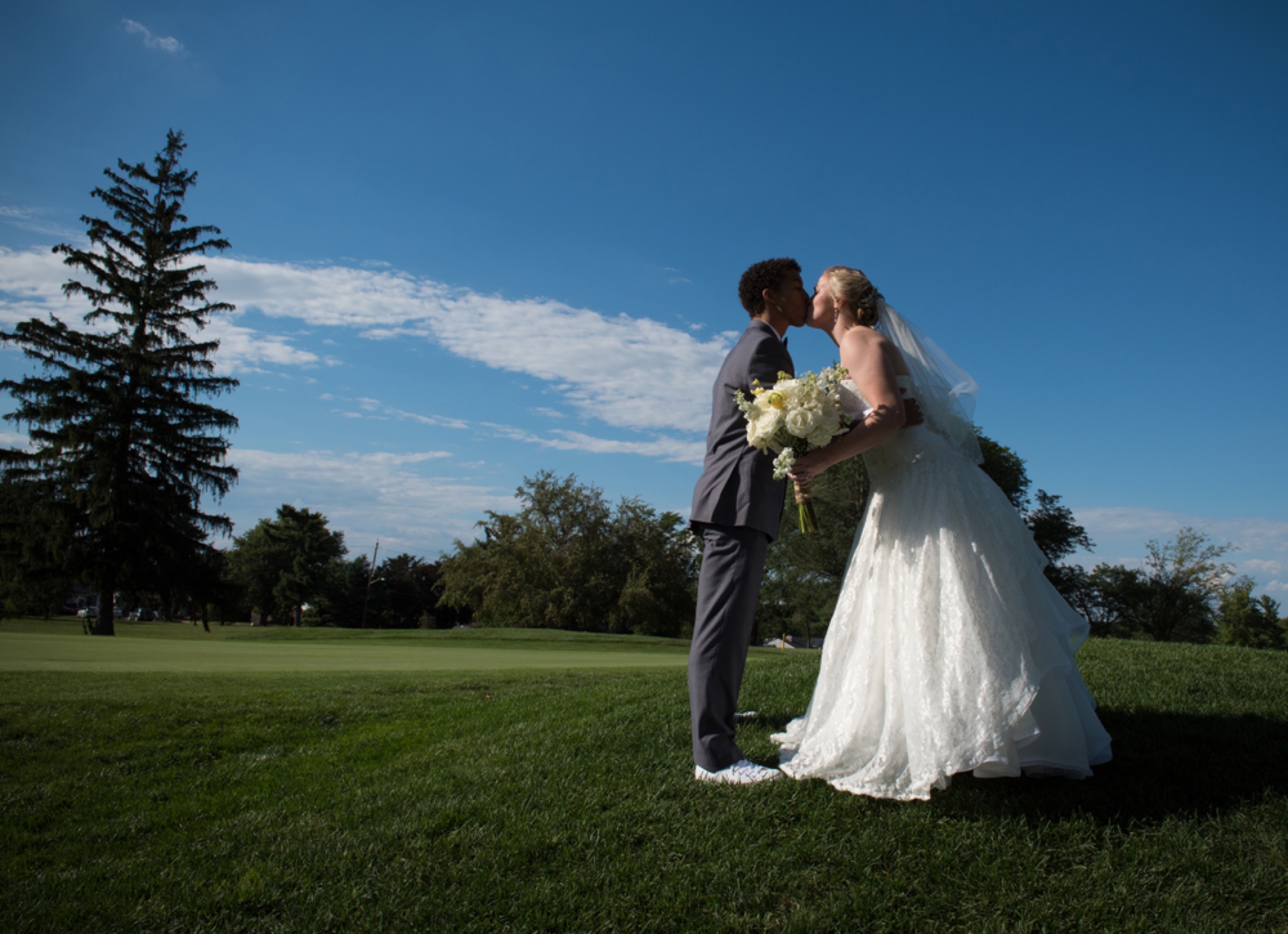 Wedding couple kissing under a blue sky