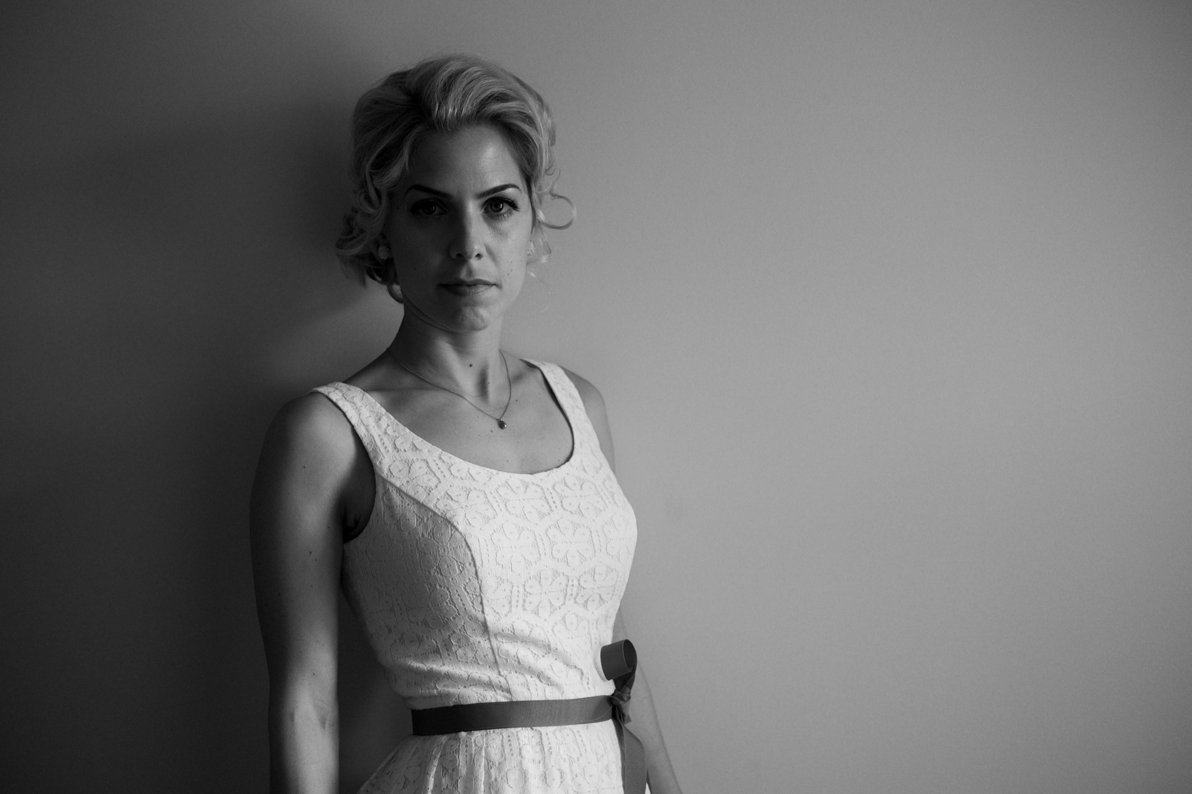 Woman in a white dress by a grey wall